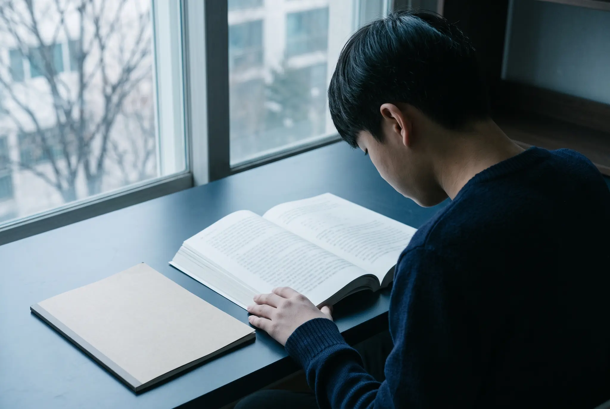 중학생이 겨울방학에 책상에서 고등학교 수학 문제를 풀며 공책에 식을 정리하는 모습